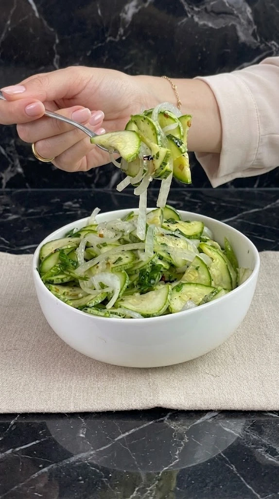 Mulher com salada de abobrinha preparada com mandoline profissional